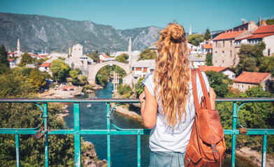 Rear view of young female tourist looking at famous bridge of Mortar in Bosnia. Travel destination, tour tourism in Europa