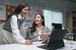 © crizzystudio - Two young businesswomen discuss the details of their planning, operations, and income during coffee breaks at their desks happily.