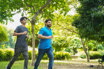 Young indian father and son running or jogging at summer park, healthy lifestyle concept. Fitness