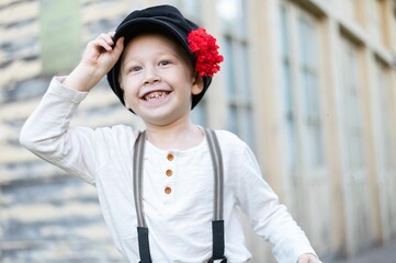 Joyful child with a flowered hat smiling outdoors.