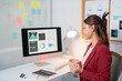 © Tj - Focused young businesswoman works on her computer in a modern office, sipping coffee while analyzing data and charts