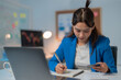 © Tj - Focused asian businesswoman multitasks with credit card and notebook, managing online transactions confidently from home office
