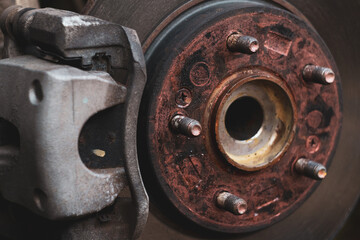 The old brake disc and caliper require service in a professional automotive workshop.