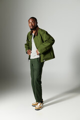 A young man dressed in stylish green attire showcases his fashion sense against a neutral backdrop.