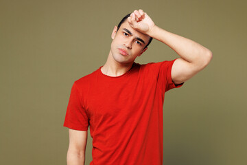 Wall Mural - Young sad middle eastern man he wearing red t-shirt casual clothes put hand on forehead suffer from headache look camera isolated on plain pastel green background studio portrait. Lifestyle concept.