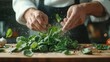© familymedia - A chef in action preparing green leaves, subtly dusted with flour in a culinary setting, highlighting the precision and artistry in modern cooking techniques.
