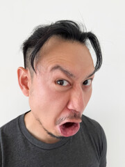 Vertical photo of asian Thai man with bun hair, making funny surprised face, curious and distrust, isolated over white background wall.