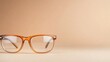 © familymedia - A pair of brown glasses with clear lenses displayed on a beige background, highlighting its simple yet stylish design without any accessories visible in the scene.