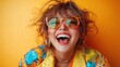 © familymedia - A vibrant woman with short hair, wearing colorful sunglasses and a patterned blouse, laughs joyfully against a bright yellow background filled with energy.