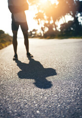 Canvas Print - Road, wellness and person with confidence for fitness, exercise and ready for marathon challenge. Legs, male athlete and runner with preparation for training, outdoor and healthy living by sunset