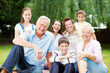 © peopleimages.com - Happy, portrait and big family with kids in nature for holiday, weekend or bonding together. Grandparents, parents and children with smile, joy or generations for picnic or outdoor vacation at park