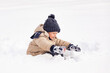 © Irina Mikhailichenko - Little boy having fun playing with fresh snow during snowfall. Snowball fight. Kid dressed in warm clothes, hat, hand gloves and scarf. Active outdoors leisure for child on nature in snowy winter day.