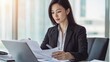 © stopcontrol - Professional woman reviewing documents at her desk, confidently preparing for an important presentation.