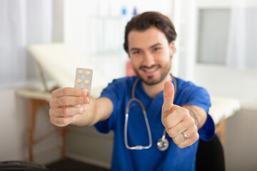 male doctor showing tablet container thumbs up