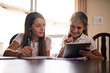 © peopleimages.com - Girls, writing and tablet for education at house with online learning, study website and research for homework. Smile, family and digital with notebook for reading assessment, information and support