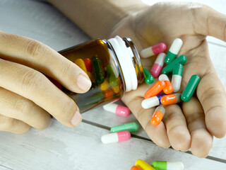 Hand pouring antibiotics from a brown glass bottle.