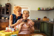 © Marko Geber - Senior lesbian couple celebrating birthday blowing cake candle at kitchen