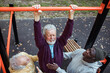 © Marko Geber - Senior men helping each other exercise on monkey bars outdoor workout