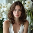 © yiam - Portrait of a beautiful woman with wavy hair, dressed in white, posing with a floral background