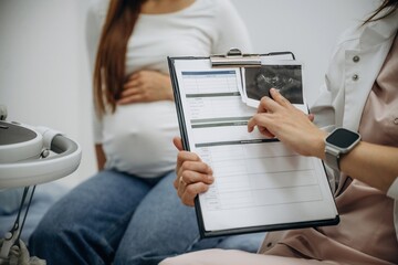 Notepad with results of scan. Pregnant woman undergoing ultrasound test