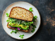 © Sarawut - delicious vegan sandwich on whole grain bread, filled with fresh greens and avocado, served on clean white plate. This healthy meal is perfect for nutritious lunch or snack