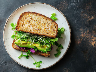 delicious vegan sandwich on whole grain bread, filled with fresh greens and avocado, served on clean white plate. This healthy meal is perfect for nutritious lunch or snack