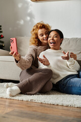 A joyful couple cuddles on the floor, capturing playful selfies in their cozy living room.