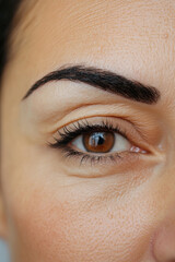 A middle-aged Hispanic woman eye with a sharp, stylish eyebrow groomed with a pencil for a bold, well-defined look. The clean lines enhance her trendy and professional style.