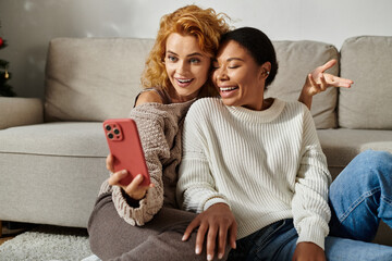 Wall Mural - Two women happily enjoying their time together while watching something on a phone.