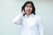 © M Alfan Setyawan - image of anxious asian young business woman dressed in white formal suit shirt grabbing her dark hair look away frightened, feeling tired of overworked, regreting mistakes she made cause trouble