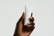© Denis - Black beauty female woman's hand holding white empty blank mockup skincare cream tube template, cosmetics commercial ad on white background.