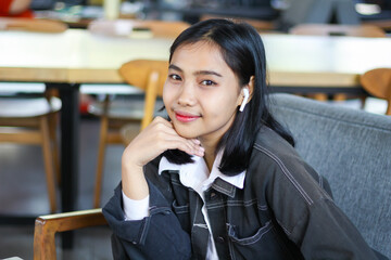 happy asian woman cafe owner sitting in the couch of cafe looking at camera with smile