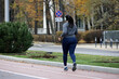 © Oleg - Girl in headphones running in autumn city, rear view. Alone runner, concept of workout and slimming