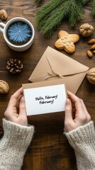 A white card welcomes February beside cookies and a coffee cup on a wooden table, surrounded by pine branches for a cozy winter feel