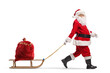 © Ljupco Smokovski - Santa Claus walking with presents in a sack on a wooden sled and looking at camera