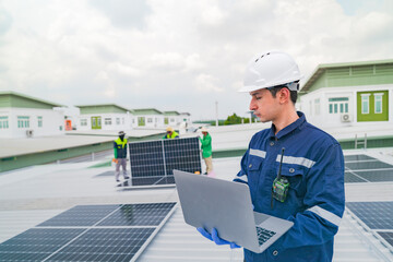 A worker in protective gear uses a laptop while inspecting solar panels on a rooftop. The image emphasizes the use of technology in managing renewable energy systems and solar power installations.