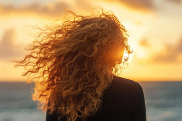 Woman with long hair standing on beach, waves crashing gently, sun setting in the background casting warm golden light, seagulls swooping overhead.