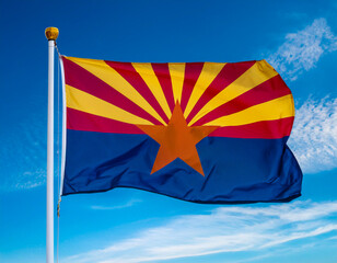 Arizona state flag waving in the wind against a blue sky background