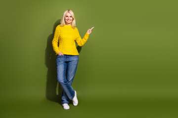 Photo of charming cute lady wear trendy sweater demonstrate empty space isolated on green color background