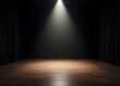 © fotoluigi868 - A modern theater stage with sleek black walls, polished wooden flooring, and a bright spotlight shining down in the center.