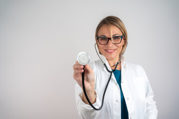 Female Doctor With Stethoscope On Isolated Background. Confident mature female doctor on grey wall background. 