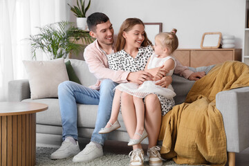 Poster - Happy parents with their little daughter hugging on sofa at home