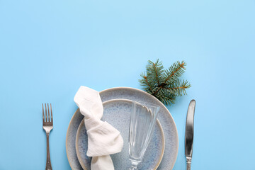 Beautiful table setting with Christmas tree branch on blue background