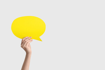 Female hand with yellow speech bubble on white background