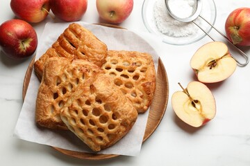 Canvas Print - Delicious puff pastries, apples and powdered sugar on white marble table, top view