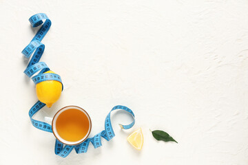 Wall Mural - Cup of diet tea, fresh lemon and measuring tape on light background. Weight loss concept