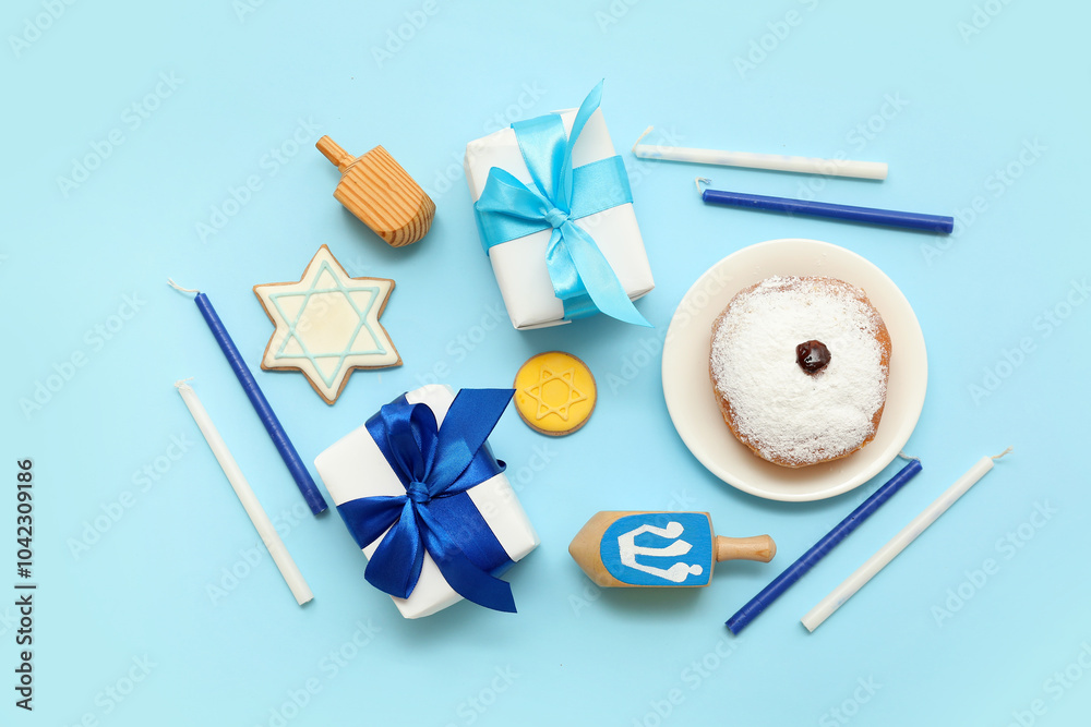 Composition for Hanukkah celebration with donut, gift boxes, candles and dreidels on blue background