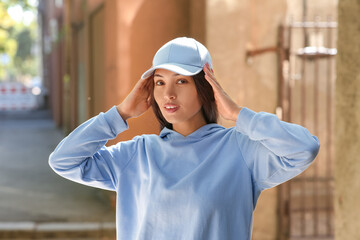 Poster - Beautiful young happy Asian woman in stylish white cap on city street