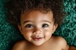 © Maelgoa - Indigenous baby boy with tan skin and curly hair, lying on a green background 5