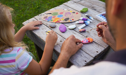 Wall Mural - Children education and home school concept. Dad and daughter paint with acrylic paints on sea rocks